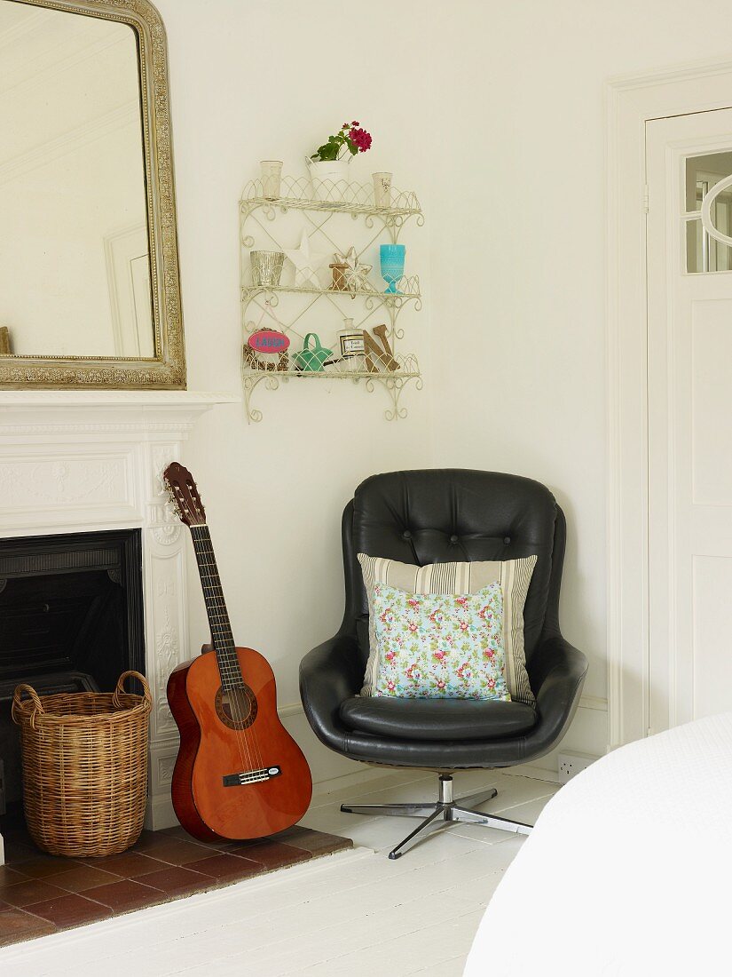 Swivel chair, guitar, wall-mounted shelves and open fireplace in corner of room