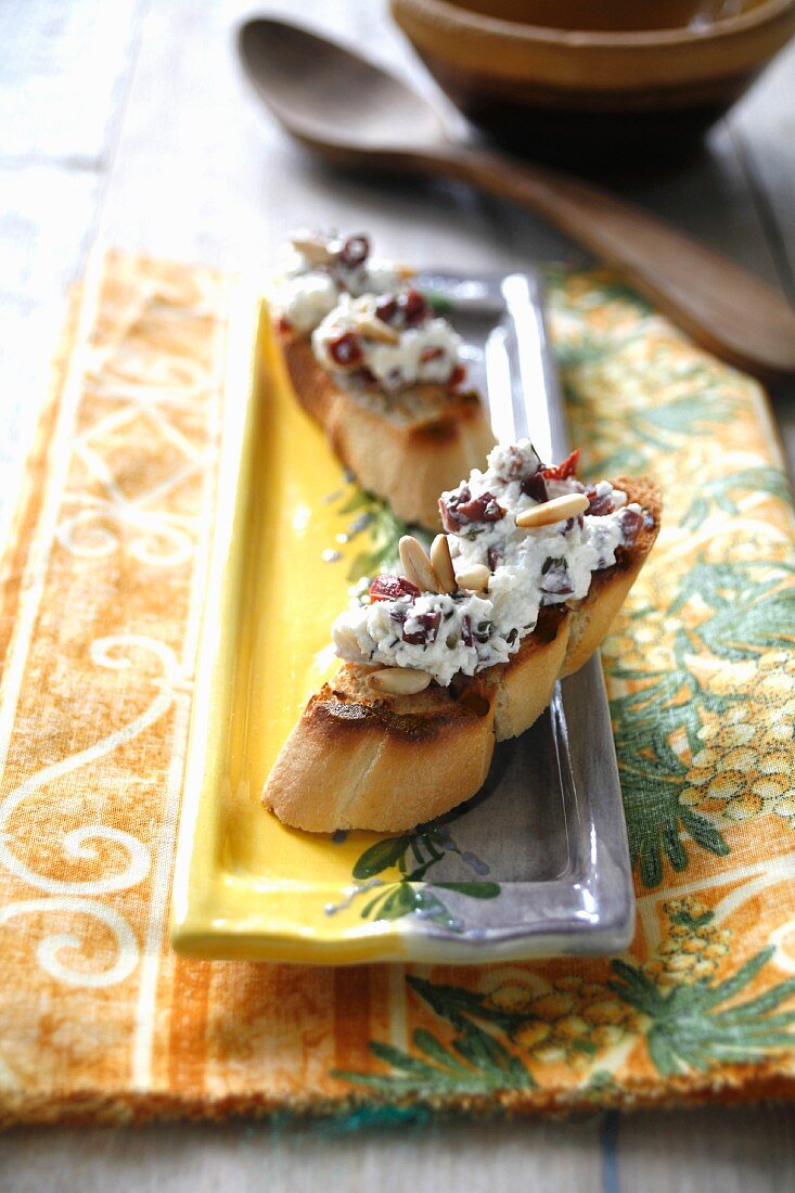 Toasted baguette slices with Gorgonzola, dried tomatoes and pine nuts