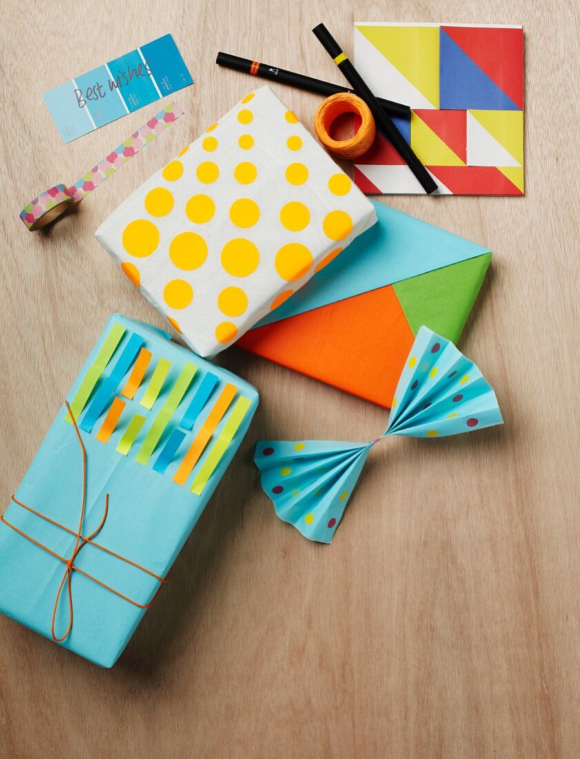 Artistically wrapped gifts using self-adhesive dots, coloured strips of notepaper and tangram-style coloured shapes