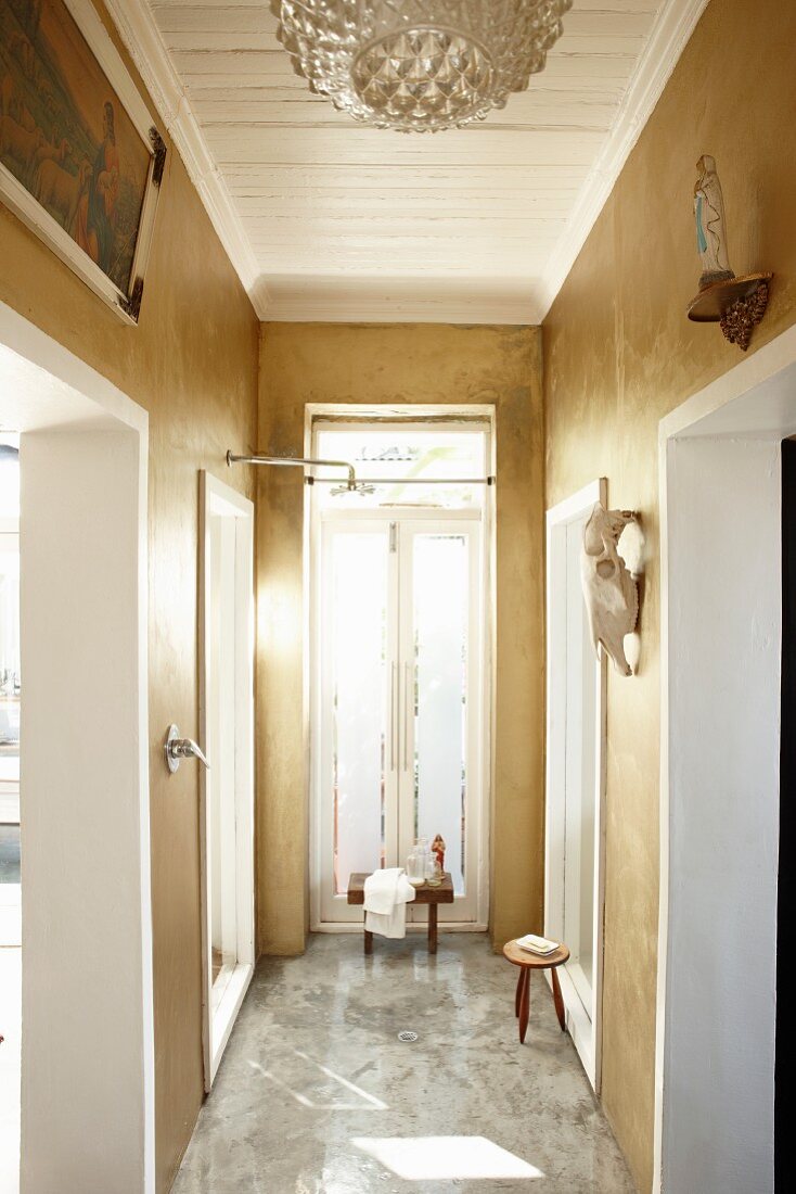 Narrow bathroom with marble floor and ochre-painted walls in grand, renovated period building