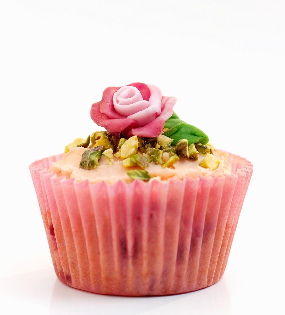 A celebration cupcake decorated with pistachios and a marzipan rose