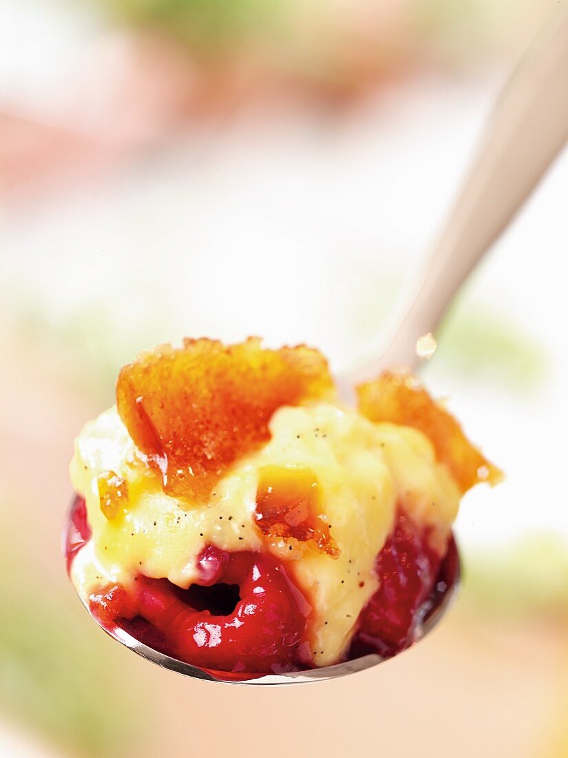 Ein Löffel Crème brûlée mit Himbeeren (Close Up)