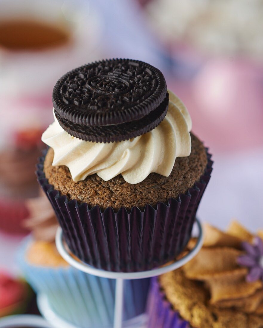 A chocolate cupcake topped with cream and a biscuit