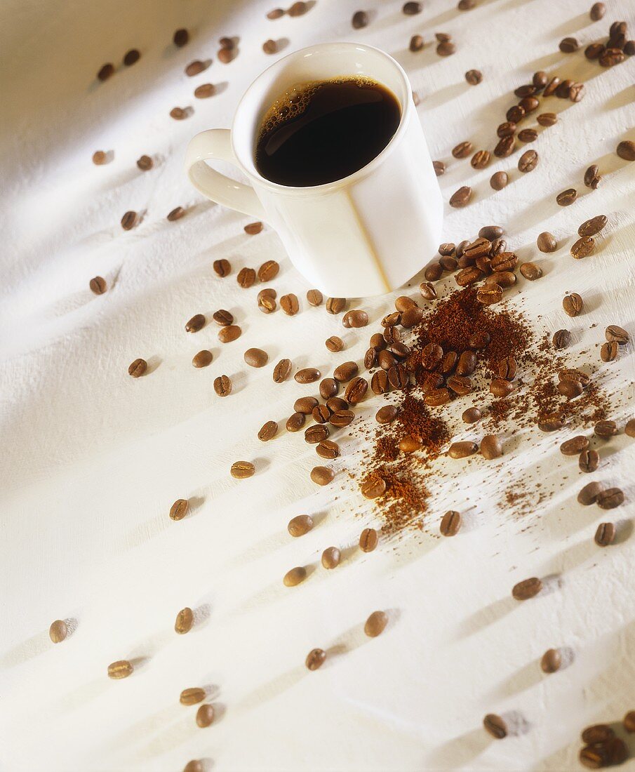 A Cup of Coffee Surrounded by Coffee Beans and Ground Coffee