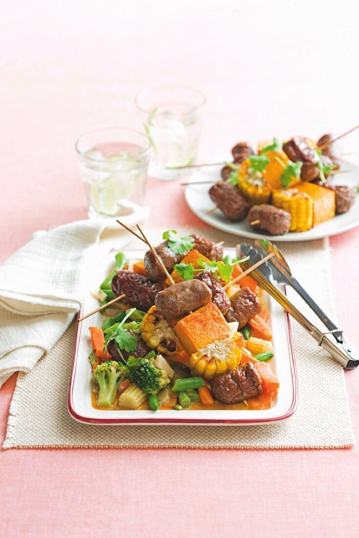 Beef sausage skewers on a bed of vegetable curry