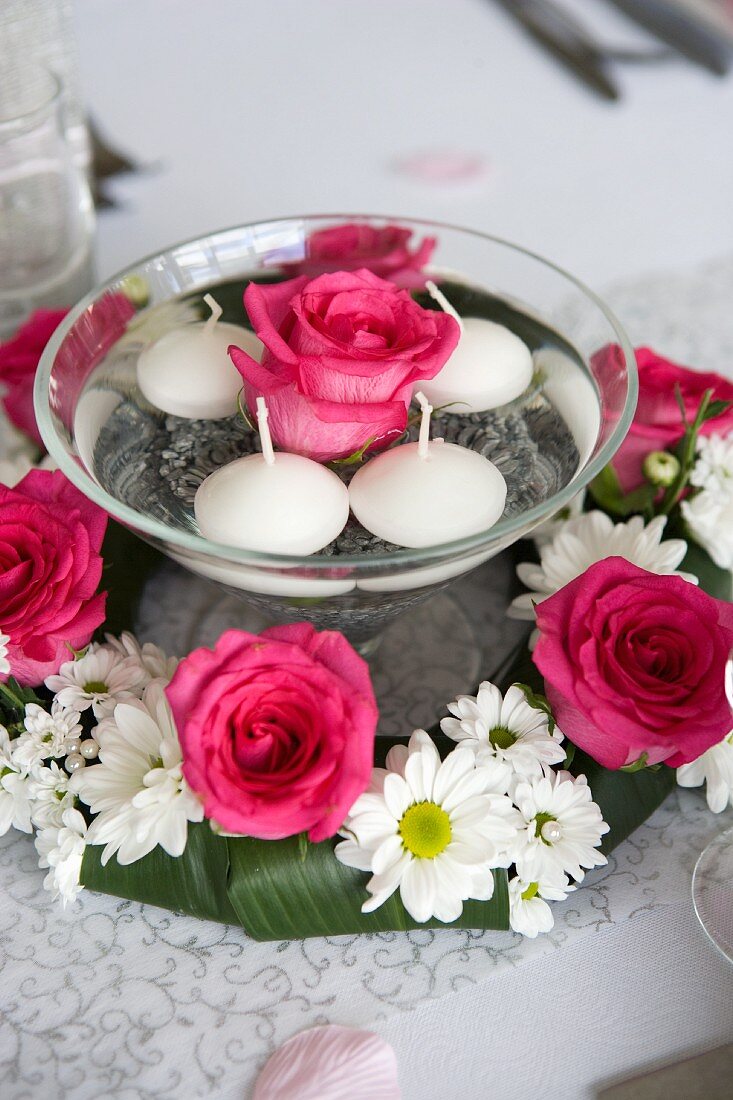 Rose and floating candles in bowl of water surrounded by wreath of roses and ox-eye daisies