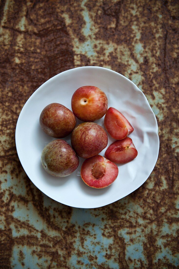 Fresh plums, whole and cut into pieces, on a plate