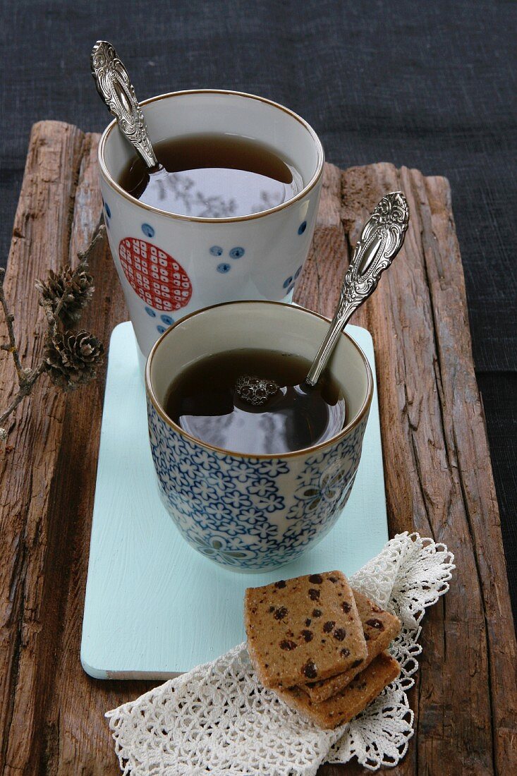Chinesische Teetassen, Teegebäck und Spitzendeckchen auf Holz