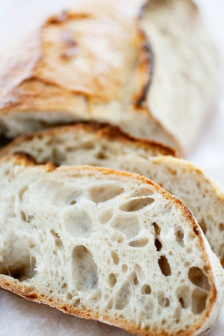 Slices from a loaf of sourdough bread with the rest of the loaf in the background