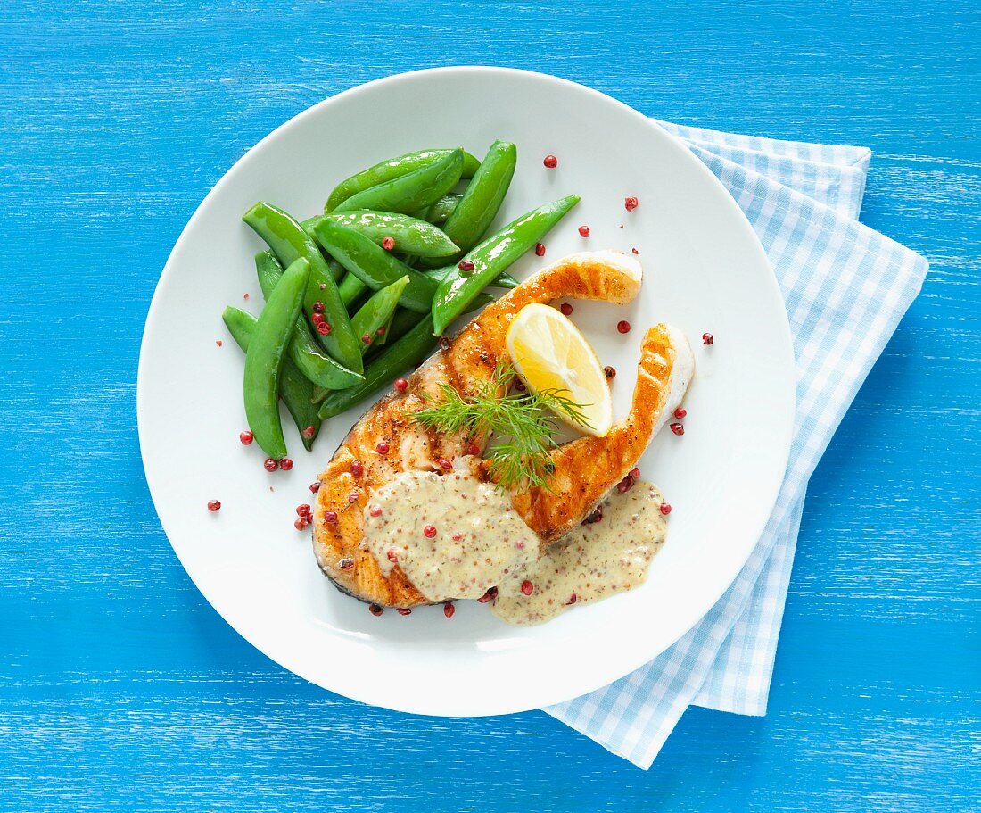 Fried salmon steak with sugar snap peas, honey and mustard sauce and red peppercorns