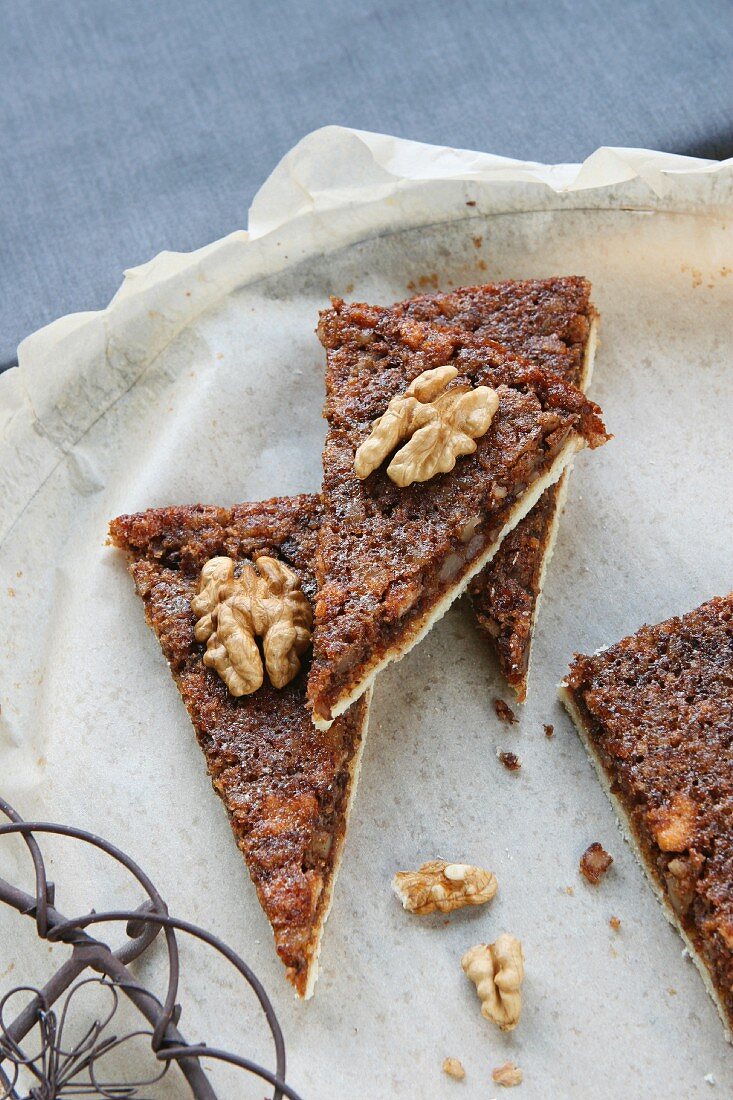 Four slices of walnut cake on grease-proof paper