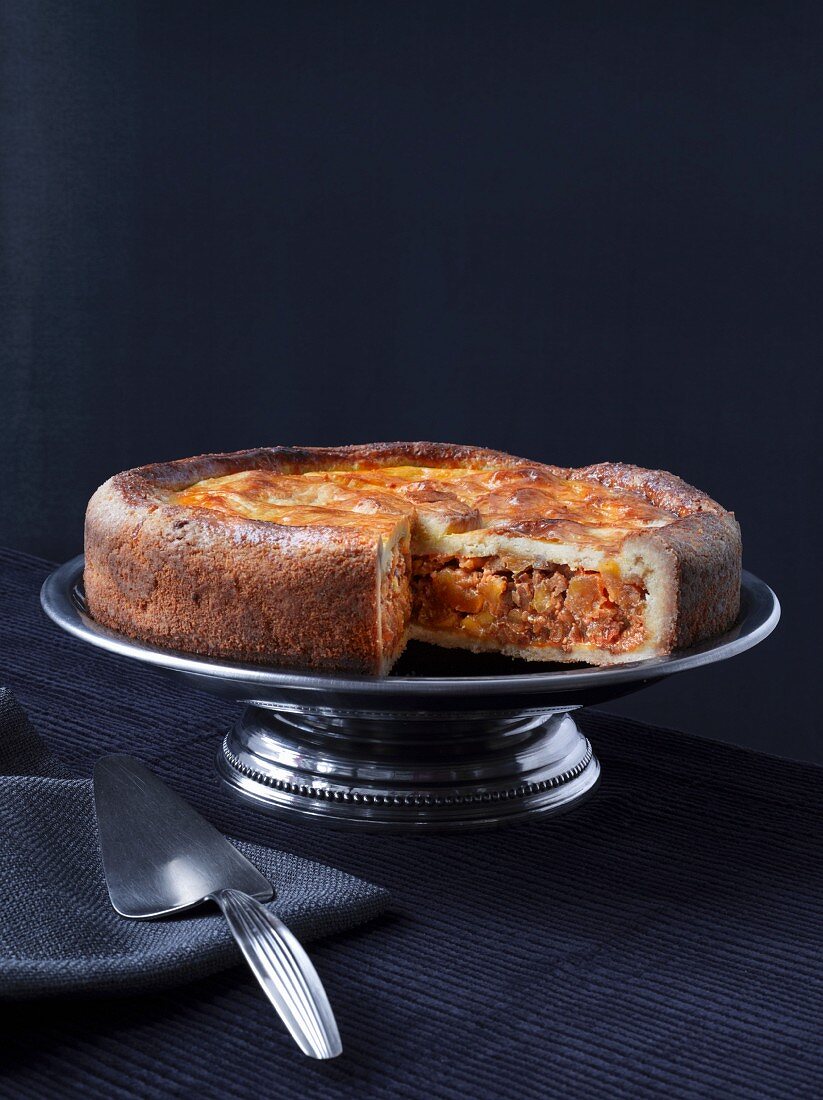 Apple and nut cake on a cake stand, with a slice cut