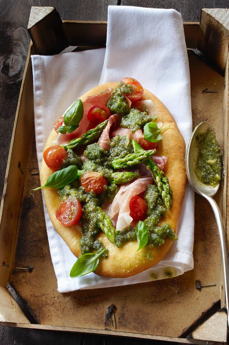Pizza topped with green asparagus and tomatoes
