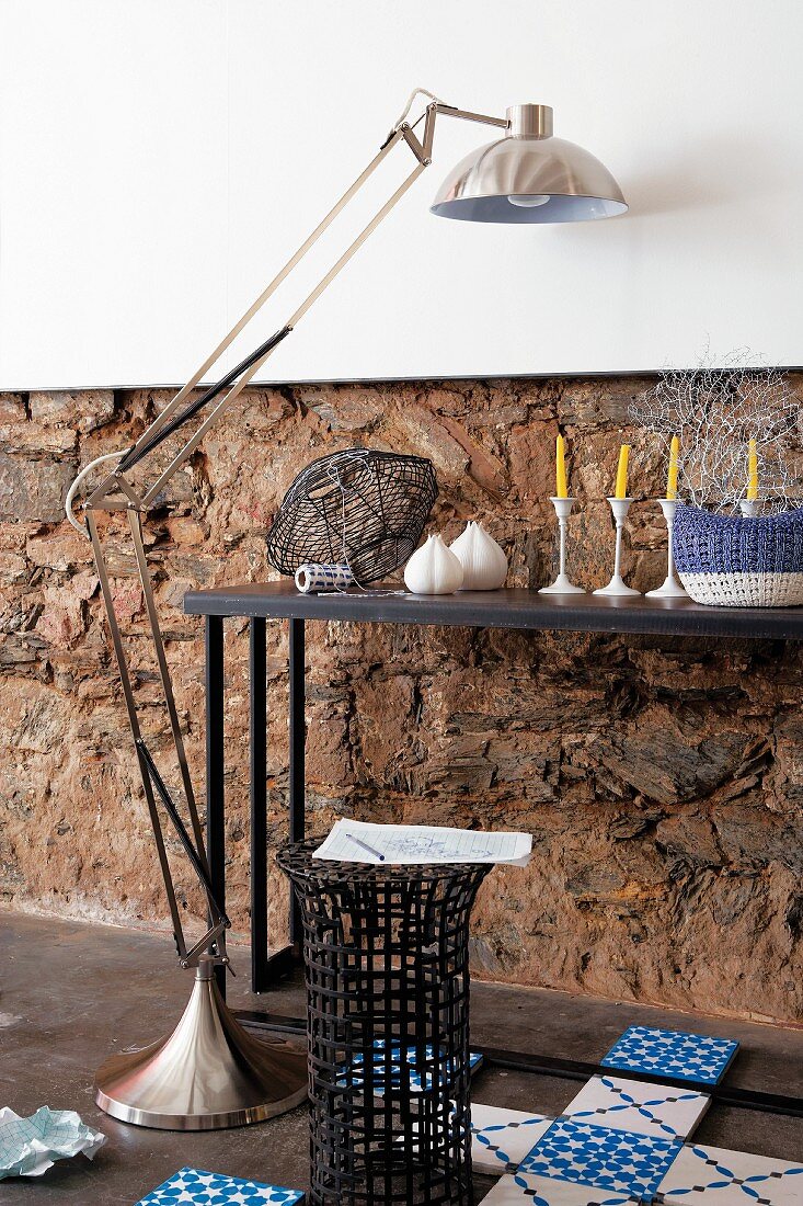 Ornaments on console table, stainless steel standard lamp, basketwork side table and Dutch-style floor tiles