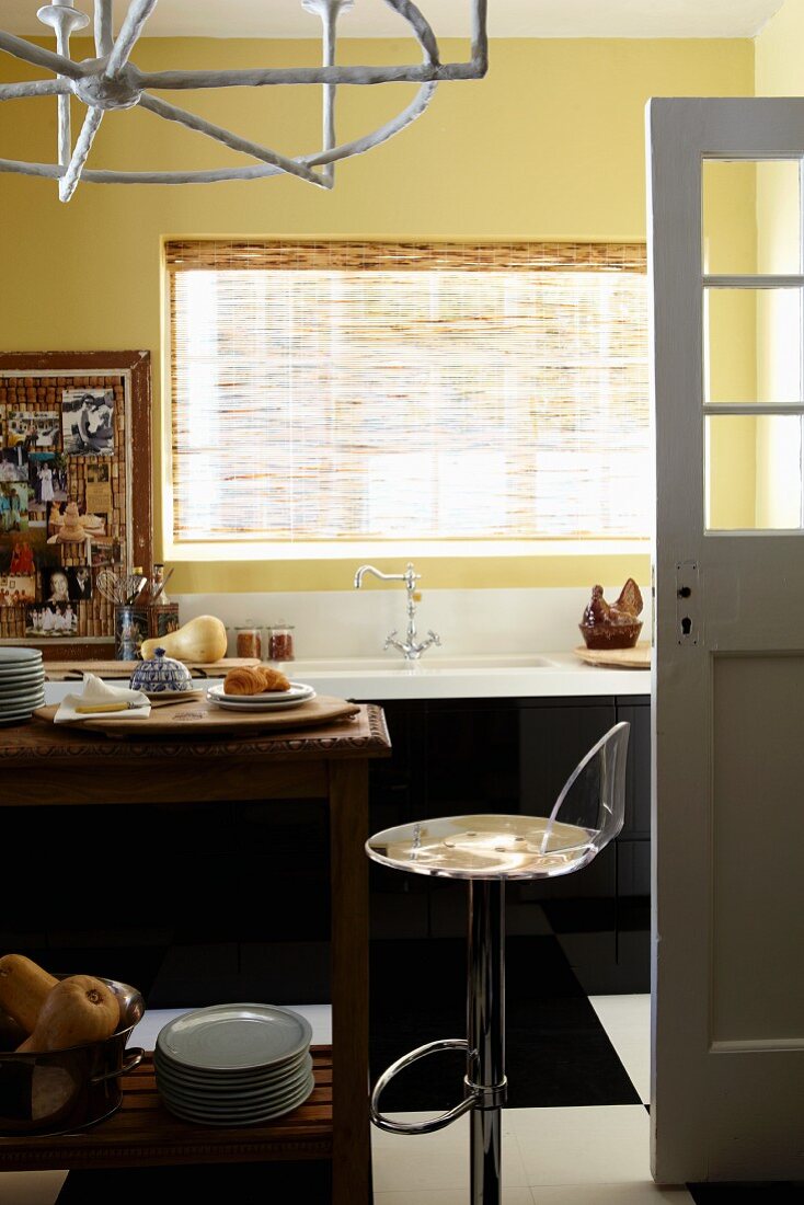 Sink, stool and narrow wooden table in corner of kitchen