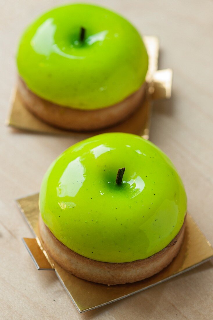 Two individual Apple pies covered with round vanilla panacotta, imitating half an apple.