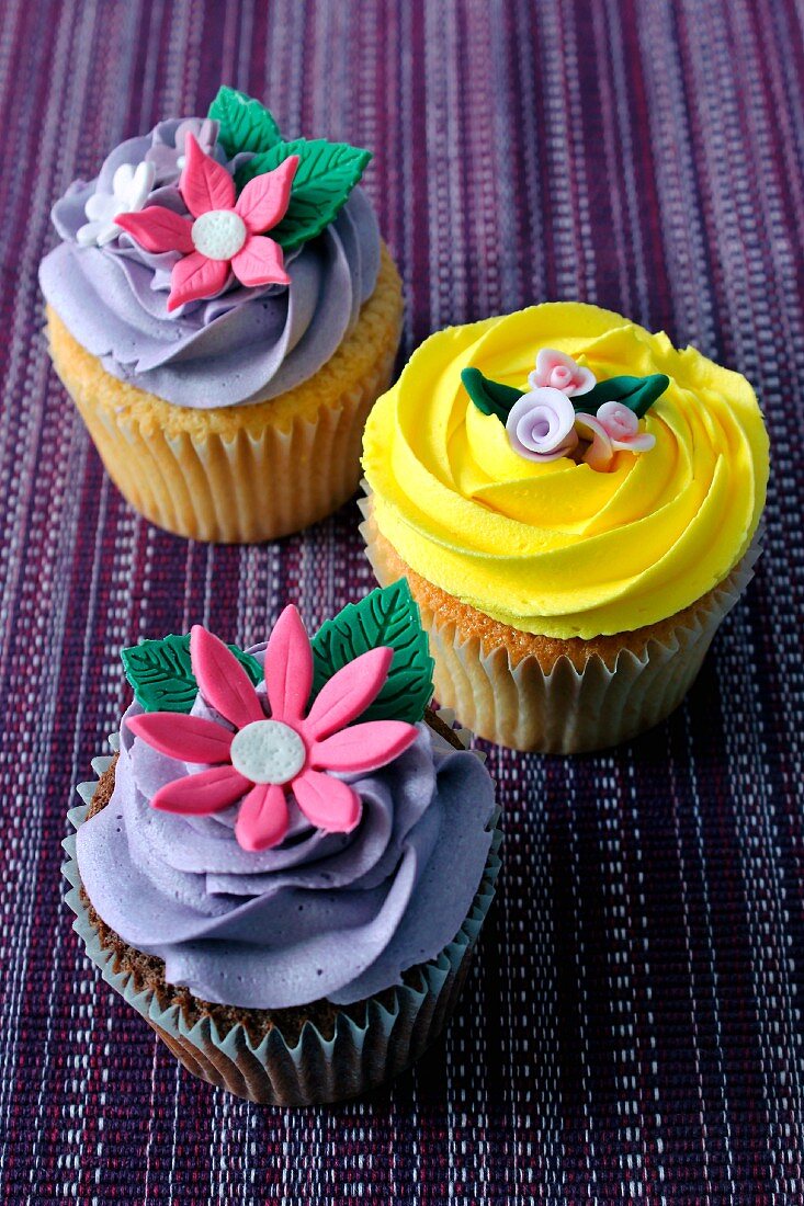 A chocolate cupcake and a lemon cupcake topped with decorative flowers