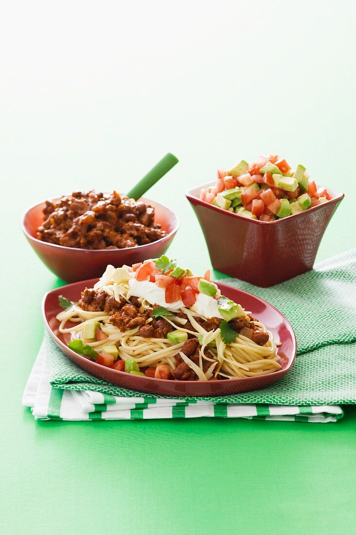 Spaghetti with minced meat, kidney beans, avocado, tomatoes and sour cream