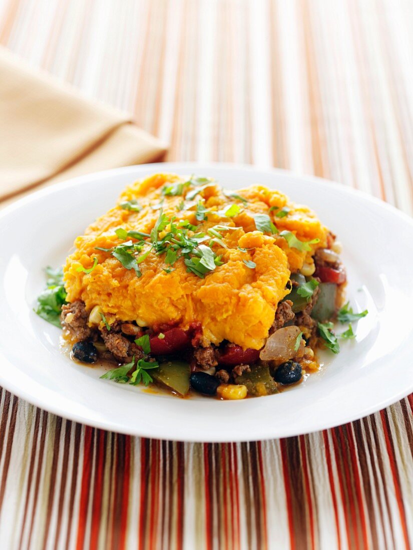 A Serving of Shepherd's Pie Topped with Sweet Potato on a White Plate