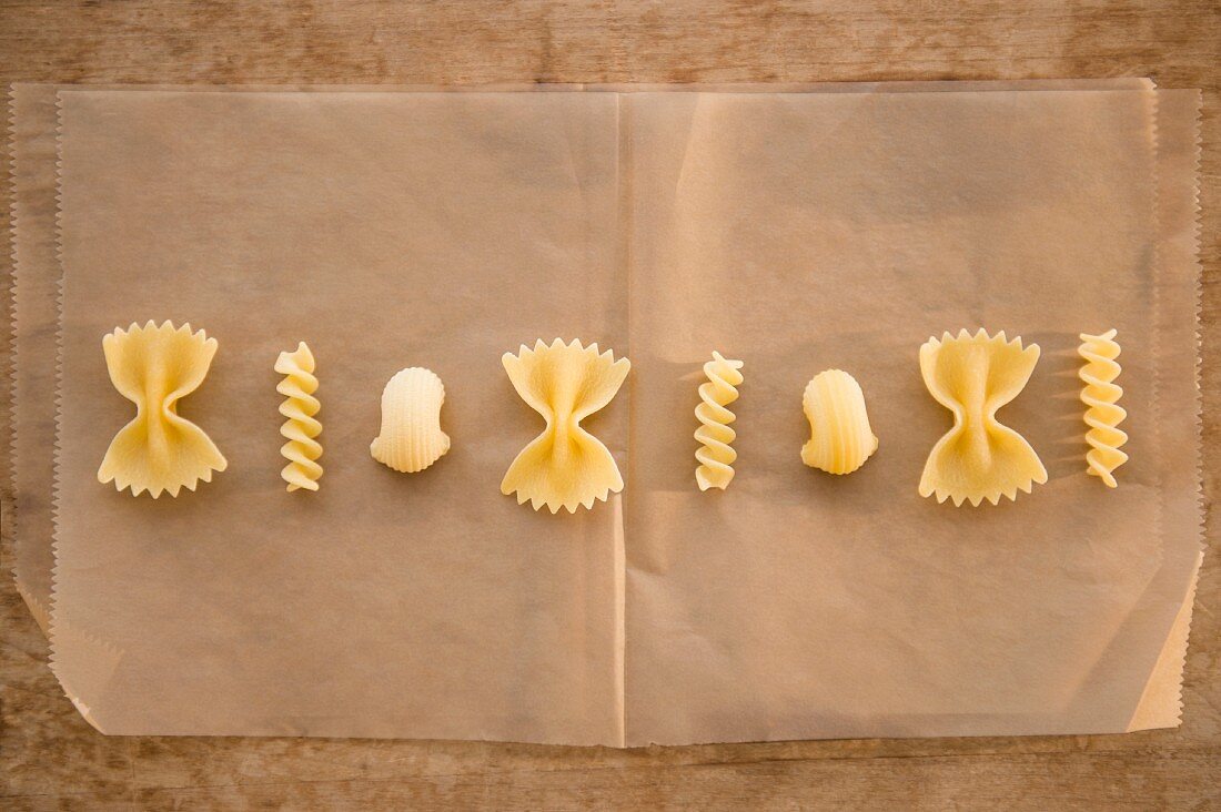 Assorted types of pasta lined up on a sheet of grease-proof paper