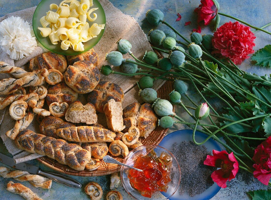 Stillleben mit Mohnkapseln, Mohnblumen, Mohnsamen, Mohngebäck, Butter und Marmelade