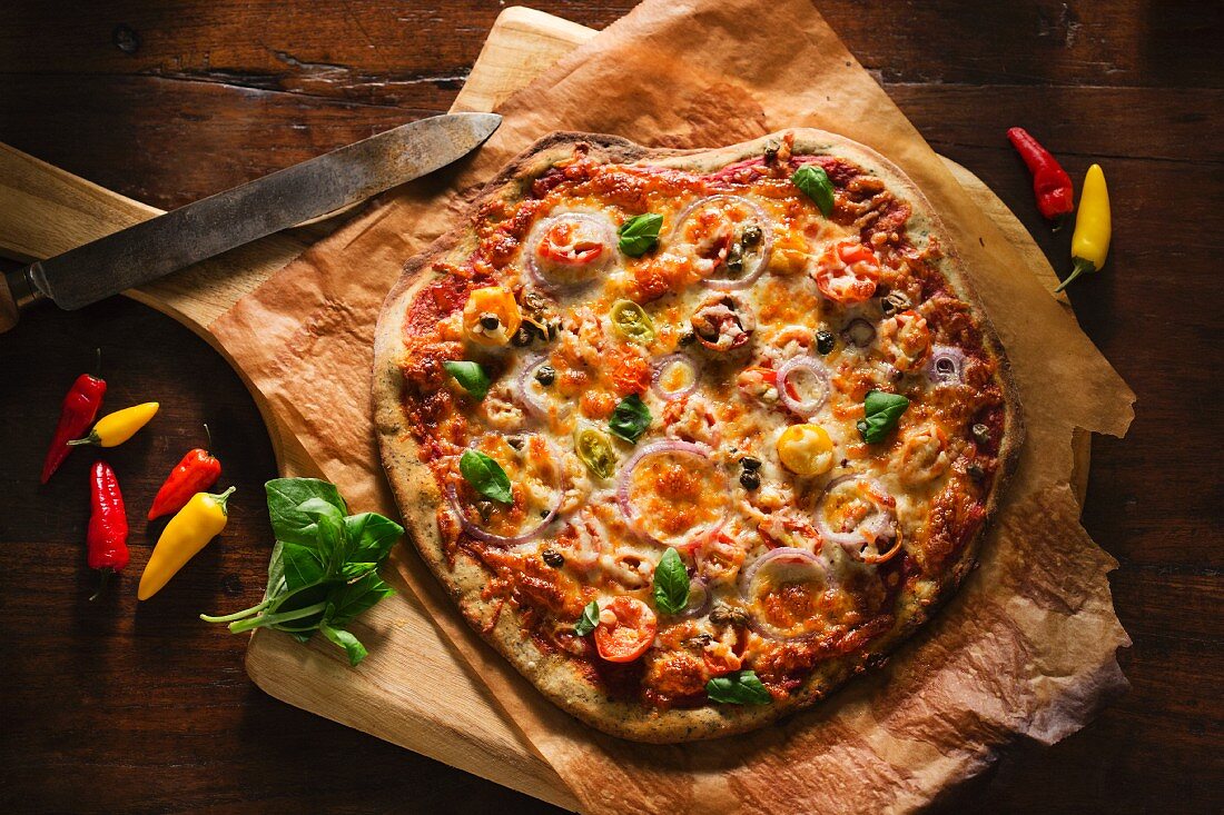 Whole Veggie Pizza on Parchment Paper on a Pizza Board; From Above