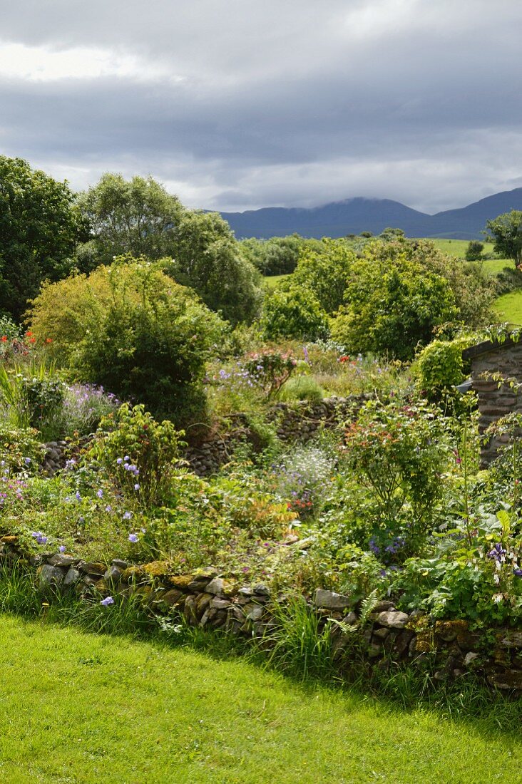 Cottagegarten und Blick in die Landschaft unter dramatischem Himmel