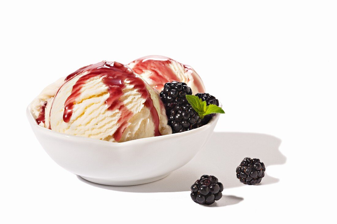 Two Scoops of Vanilla Ice Cream with Chambord Sauce and Blackberries; White Background