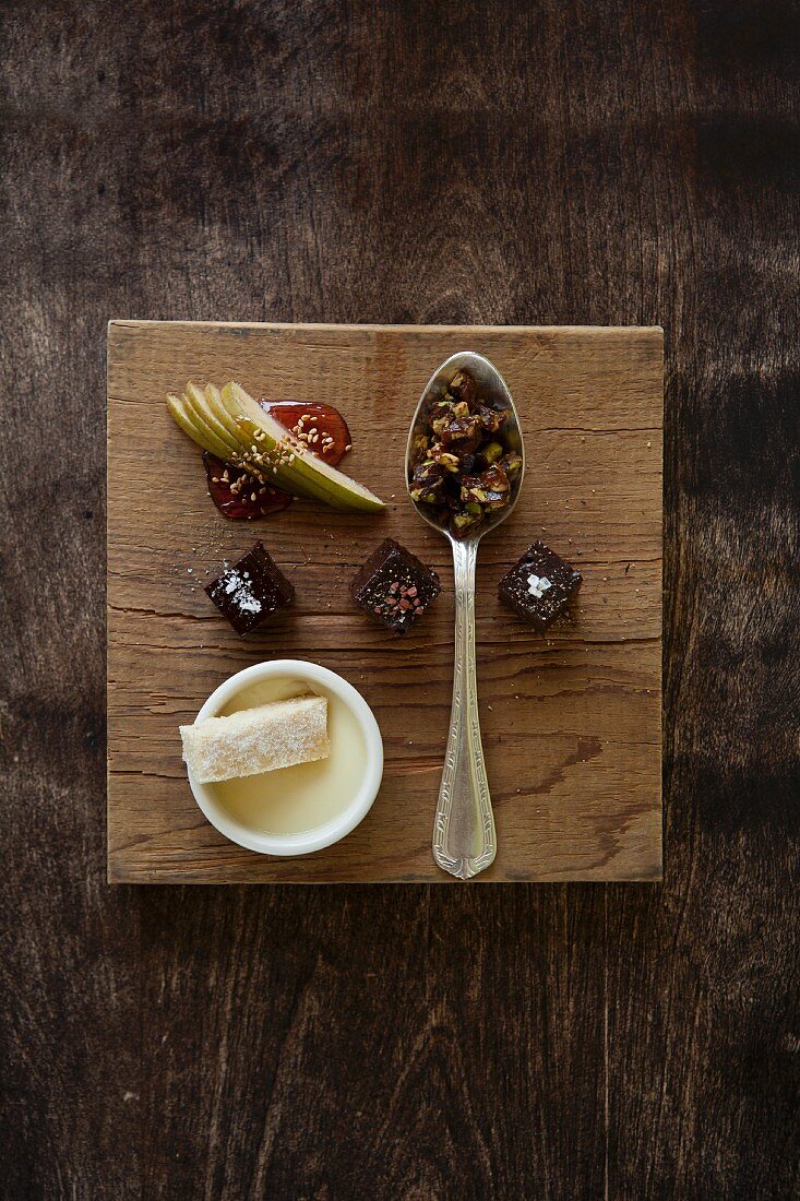 Dessertvariationen auf Holzbrett: Schokolade Boka Negra, Pistazienkrokant, Blutorangen-Pannacotta und Shortbread