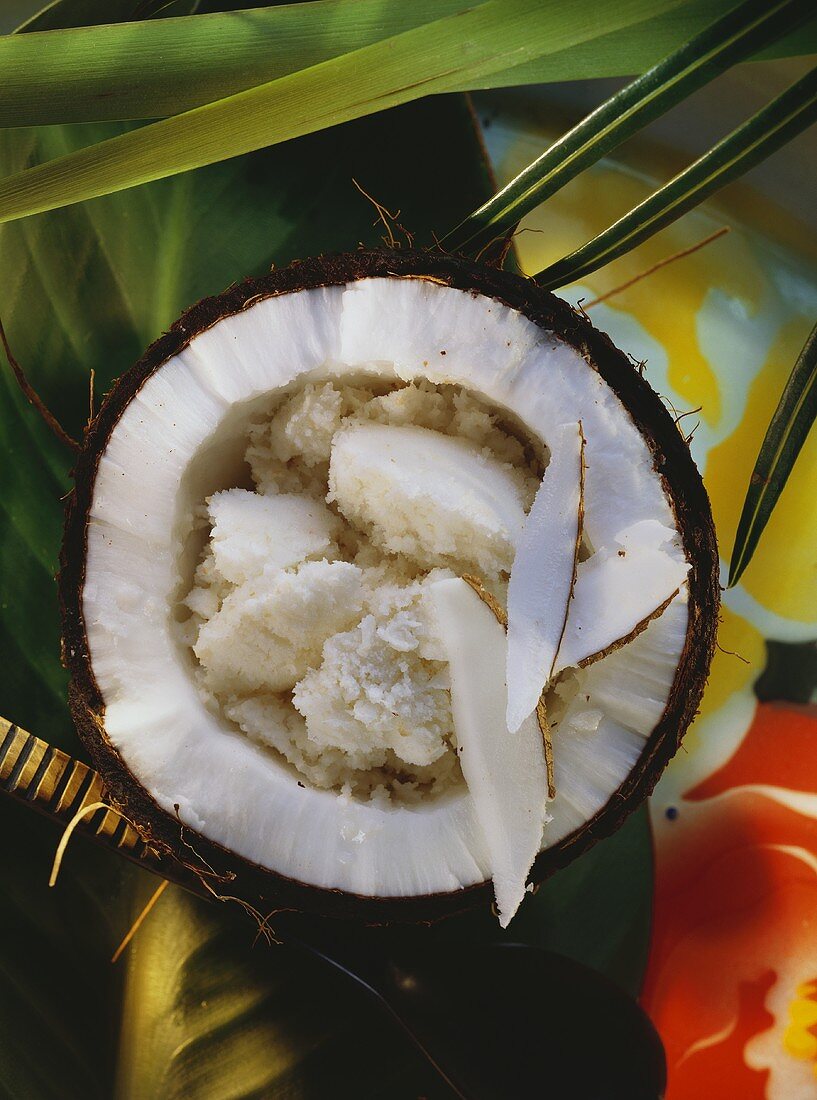 Kokosmilch-Sorbet in Kokosnußhälfte; Deko: Grüne Blätter