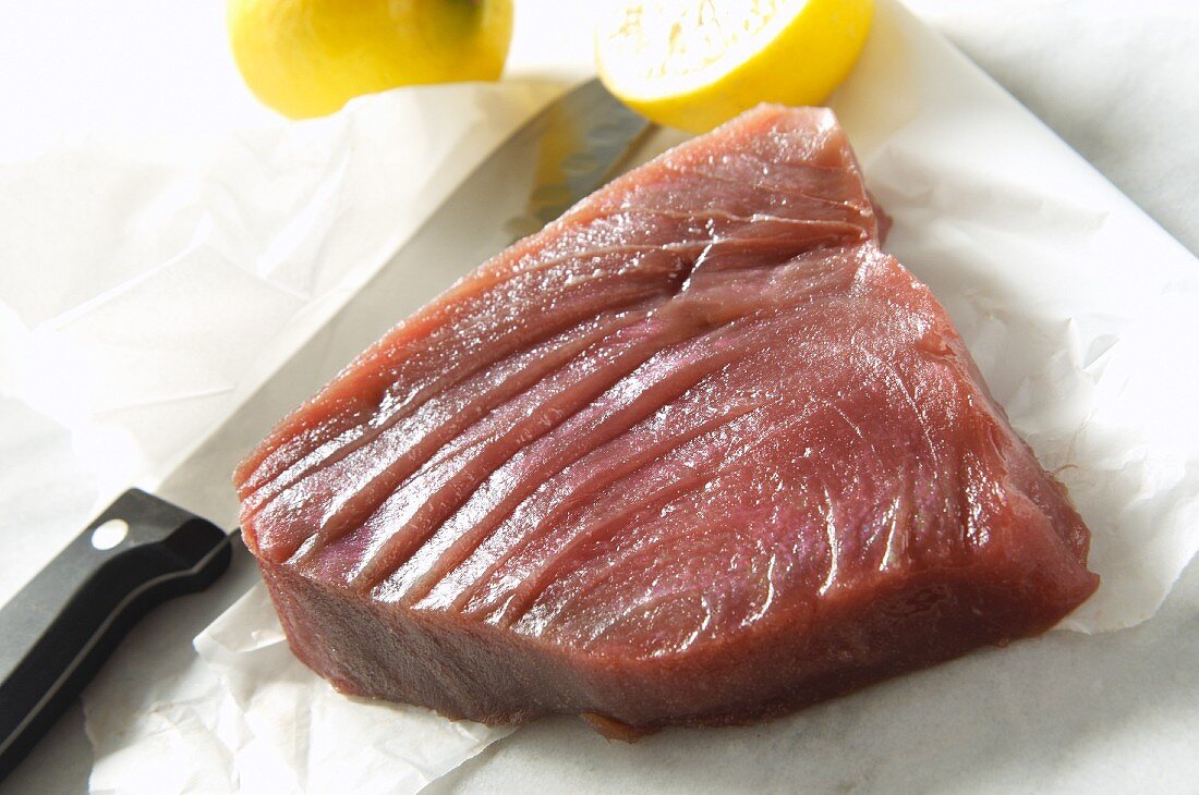 Rohes Thunfischsteak mit Messer und Zitronen