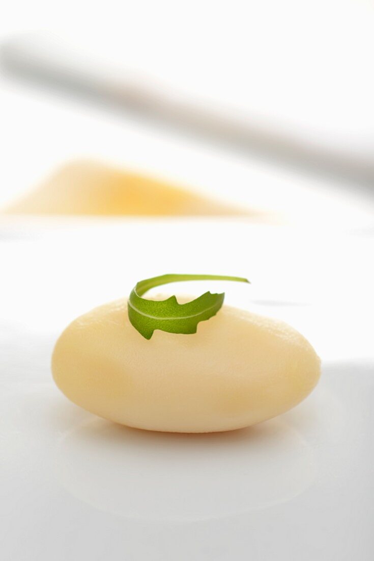 A boiled potato topped with a leaf of rocket