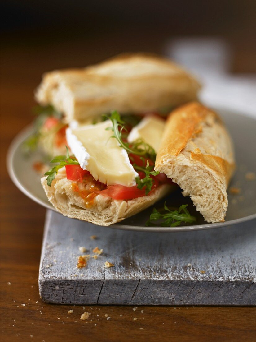 A baguette sandwich filled with brie and tomatoes