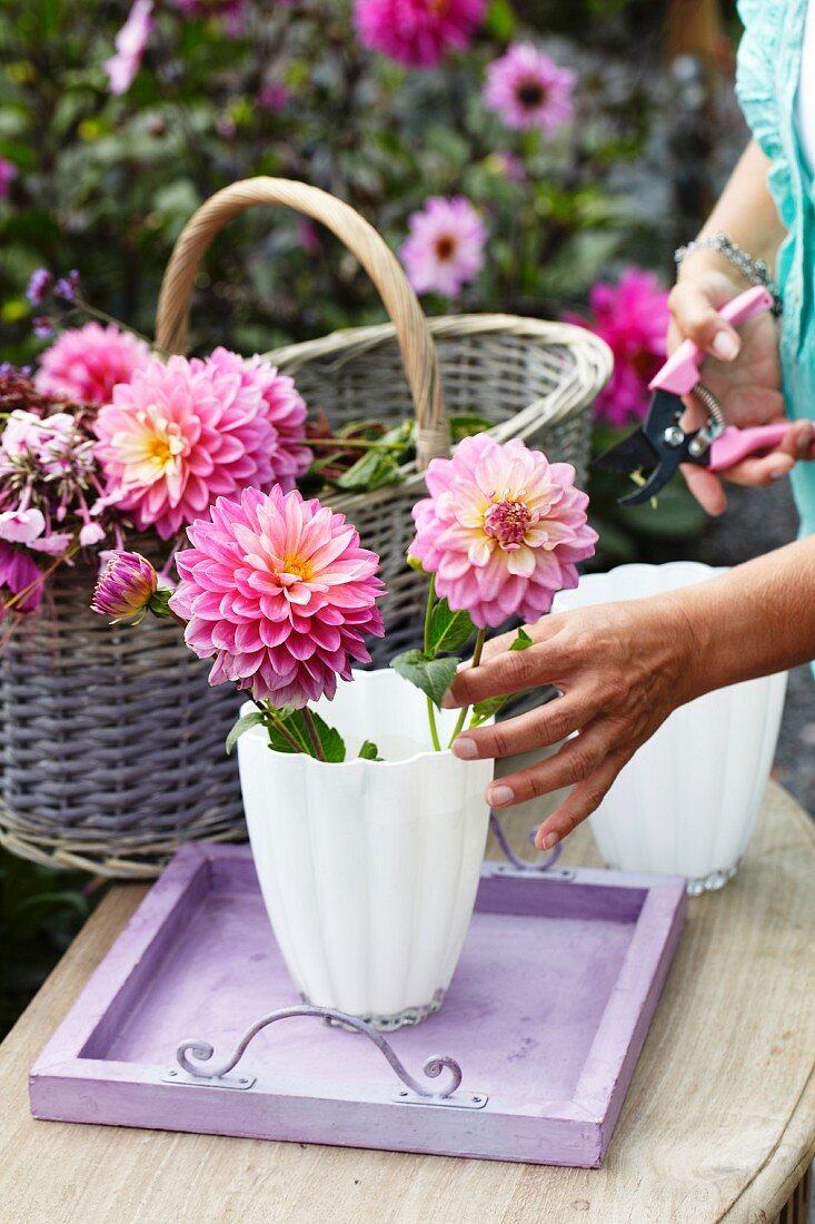 Frau arrangiert Dahlien in einer Blumenvase im Garten