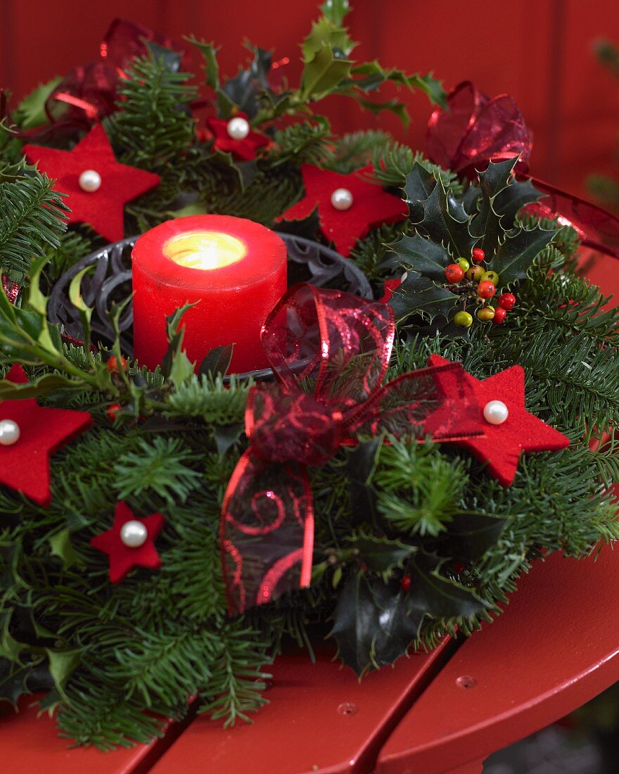 Advent wreath with candle and red felt stars on wooden table