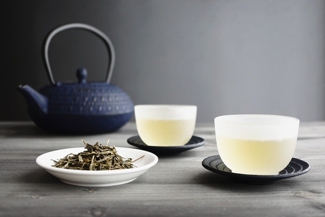Zwei Tassen Grüntee, Teeblätter und japanische Teekanne