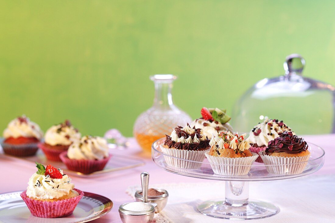 Verschiedene Cupcakes auf Tellern & Kuchenständer