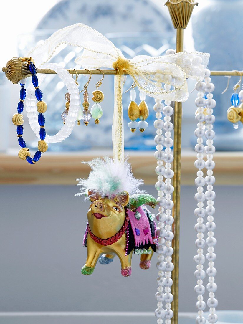 Tierfigur aus Metall neben Ohrringen und Halsketten auf Schmuckständer gehängt