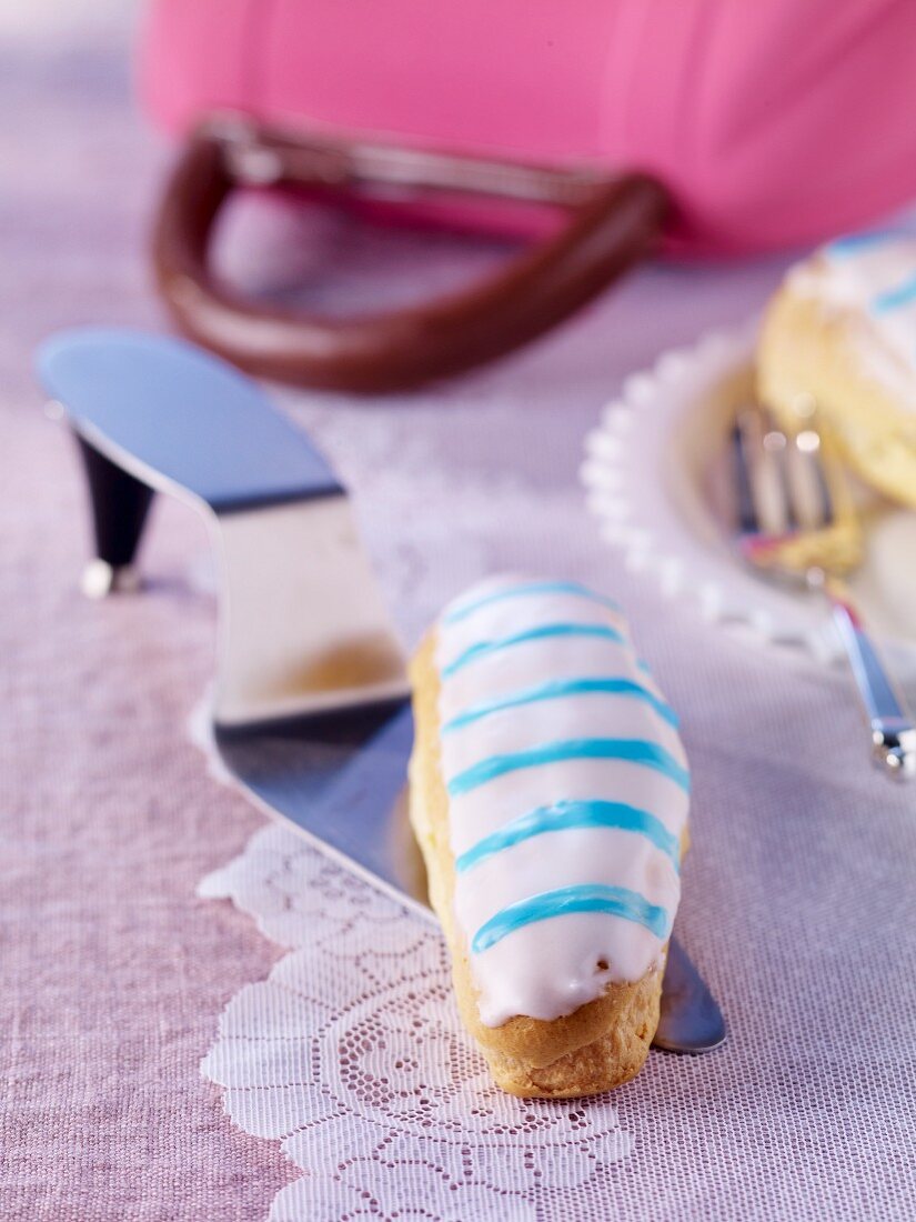 An éclair on a cake slice with a handbag to the rear