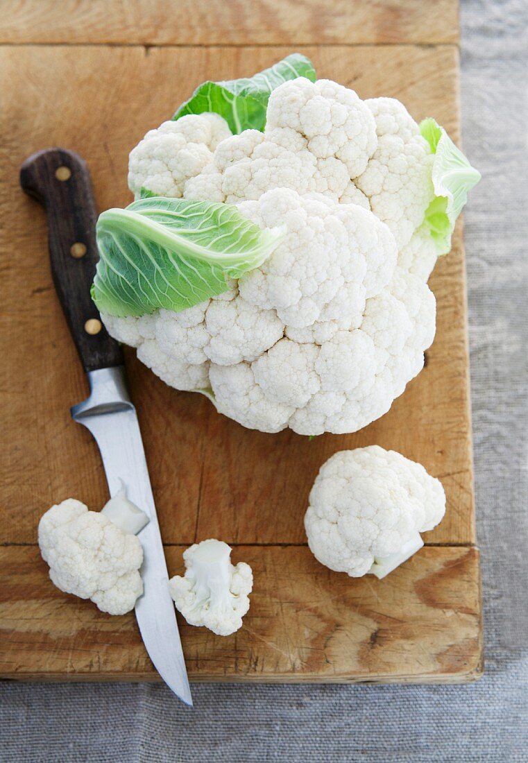 Cauliflower and a knife on a chopping board