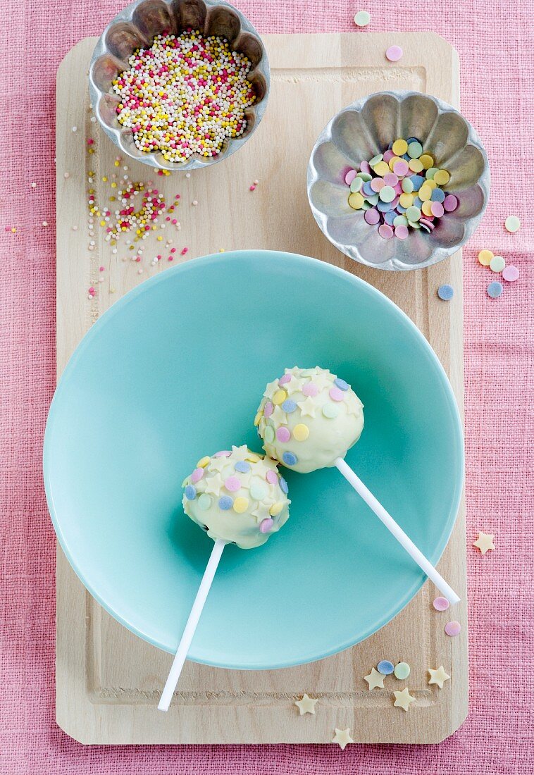 Cake pops covered in white chocolate with chocolate stars and sugar confetti