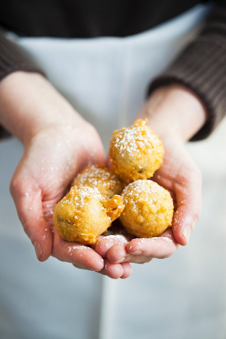 Hands Holding Beignets Sprinkled with Powdered Sugar