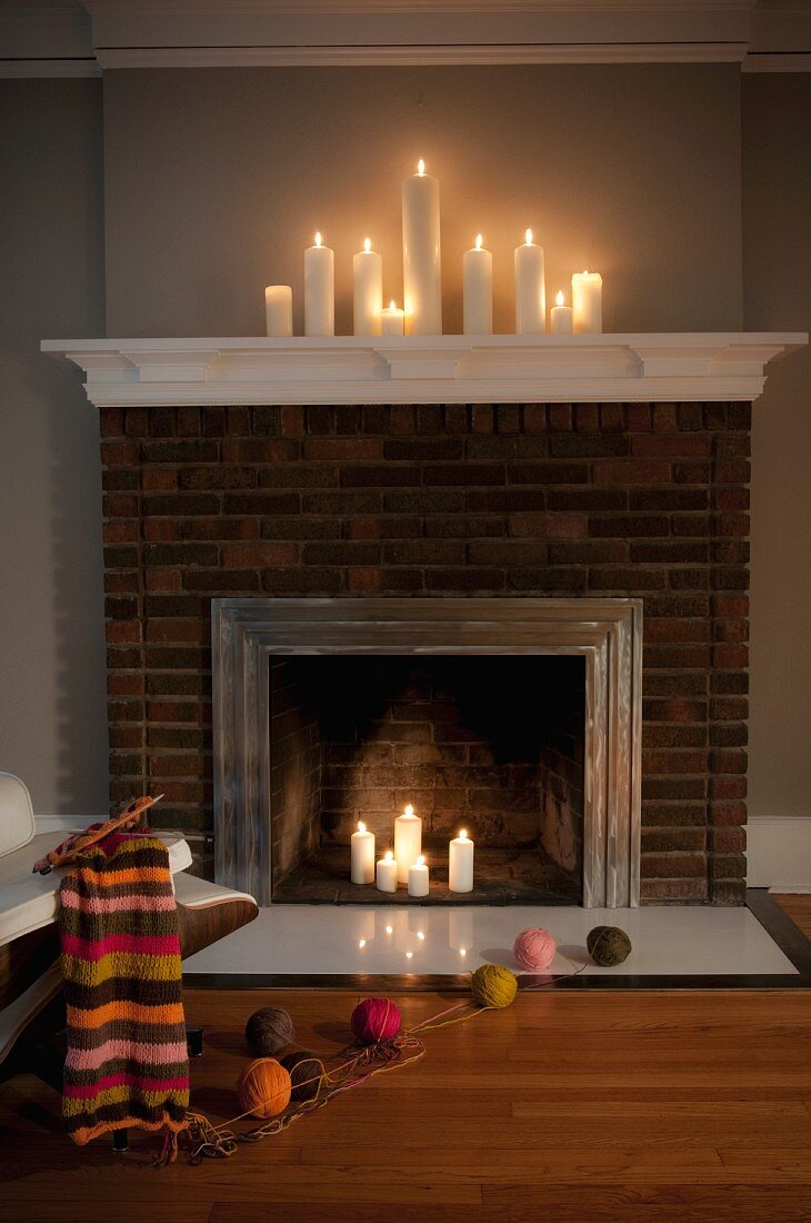 Candlelit fireplace with knitting and balls of wool on floor