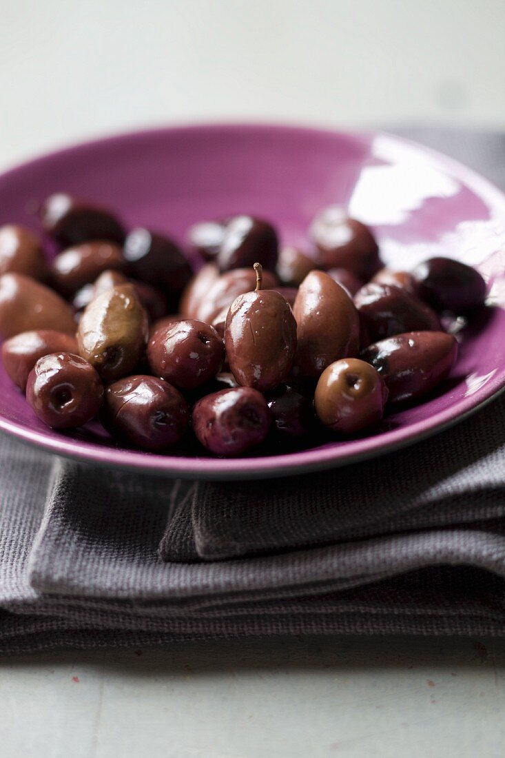 Black olives on a purple plate