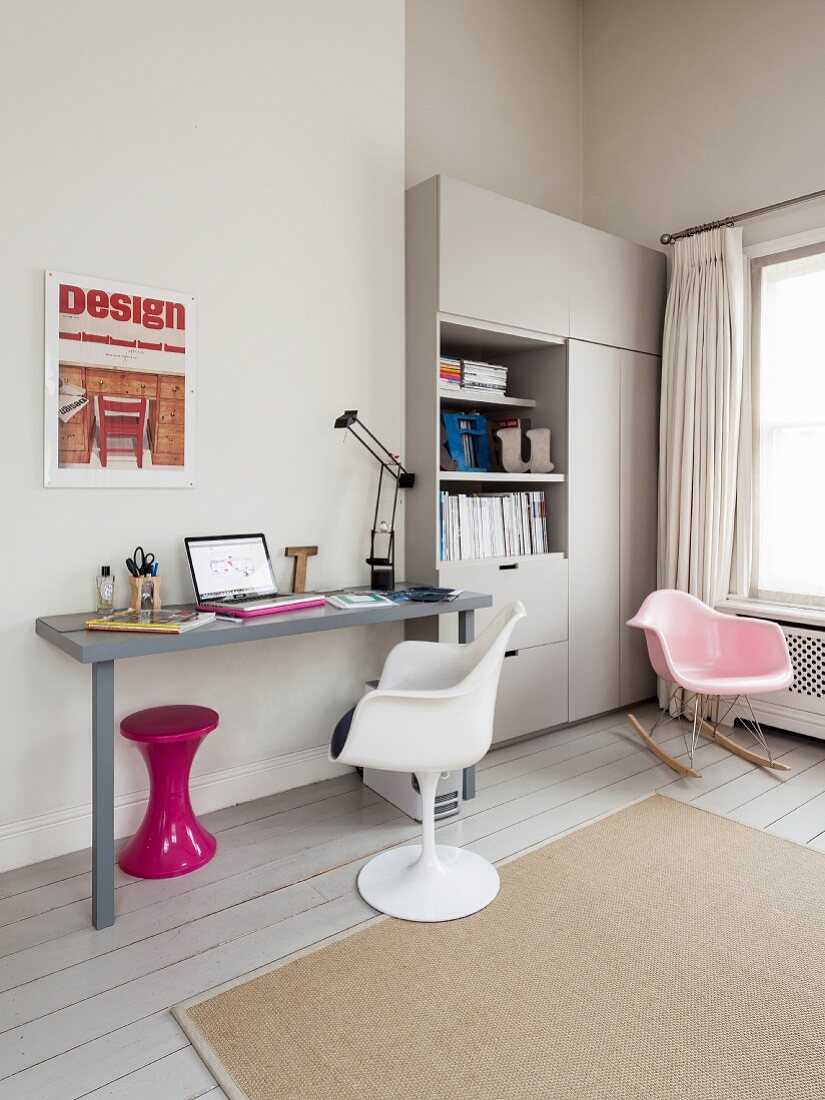 Room corner with serene gray color scheme, splash of color provided by a retro stool under the writing desk and classic swivel chair in front of an office cabinet