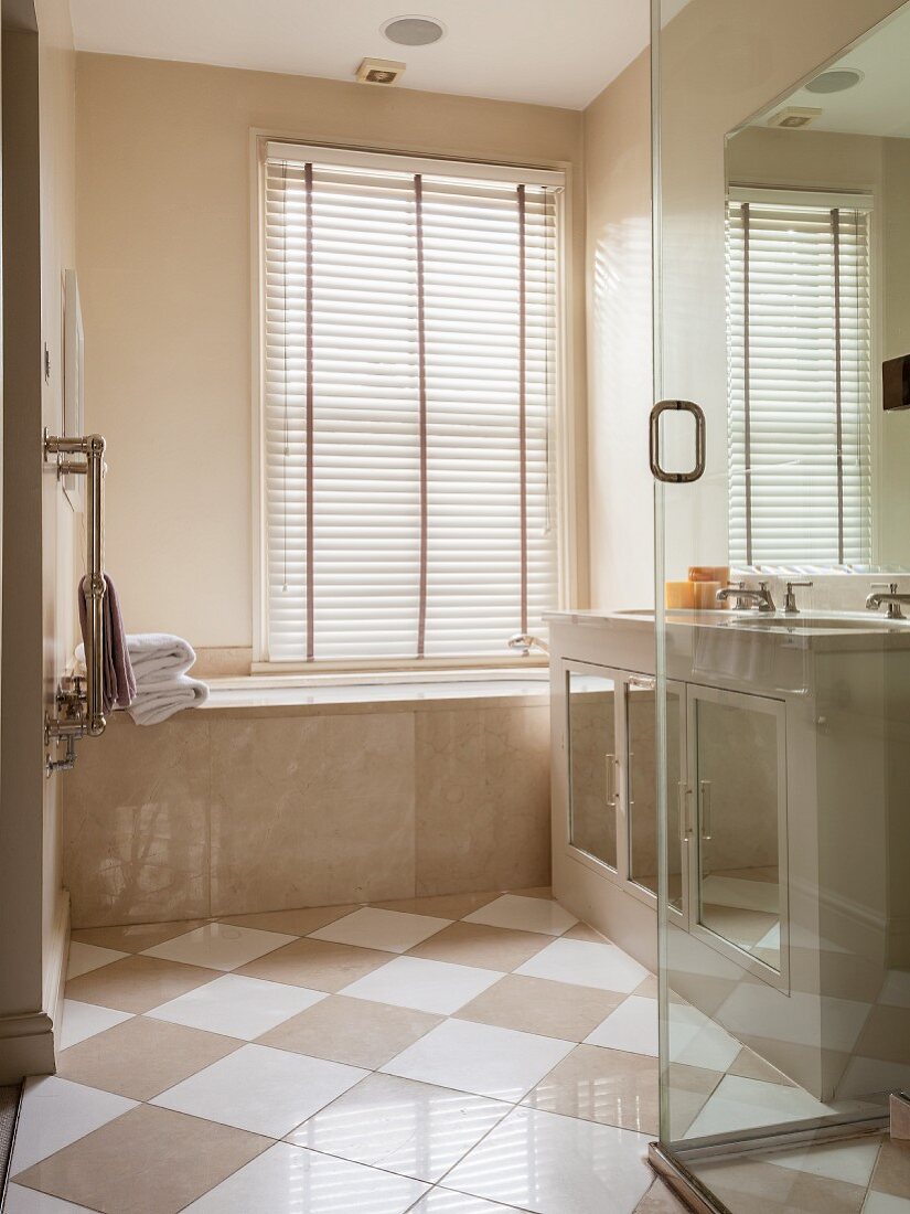 Elegantes Badezimmer mit marmorverkleideter Wanne und diagonal verlegtem Fliesenboden