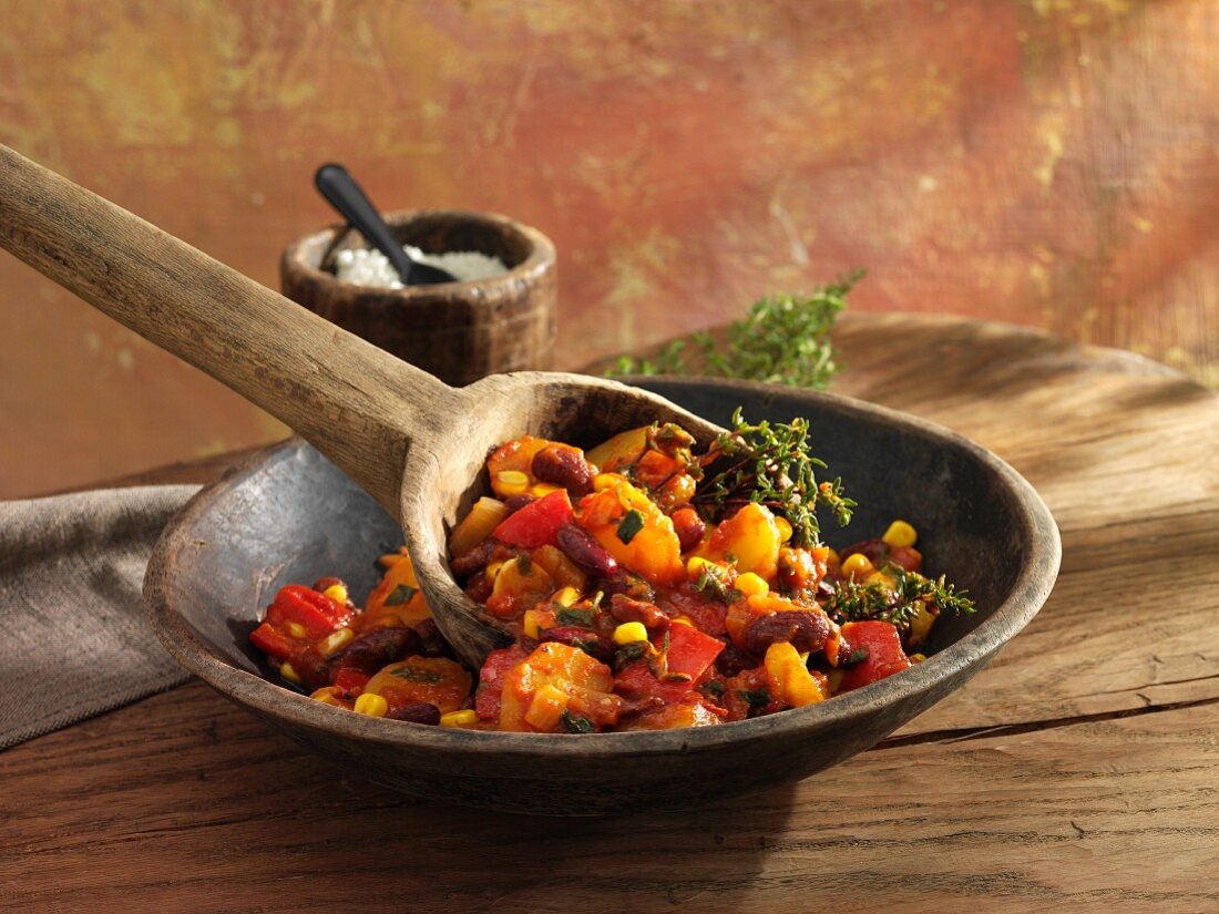 Bean stew with kidney beans, peppers and sweetcorn in a wooden bowl