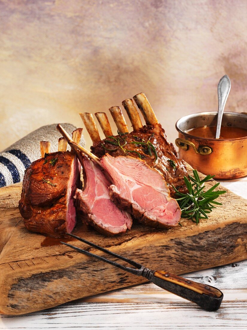Rack of lamb, cooked pink, on a wooden board