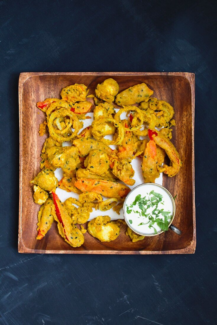 Gemüsepakora mit Raita in Holzschale (Aufsicht)