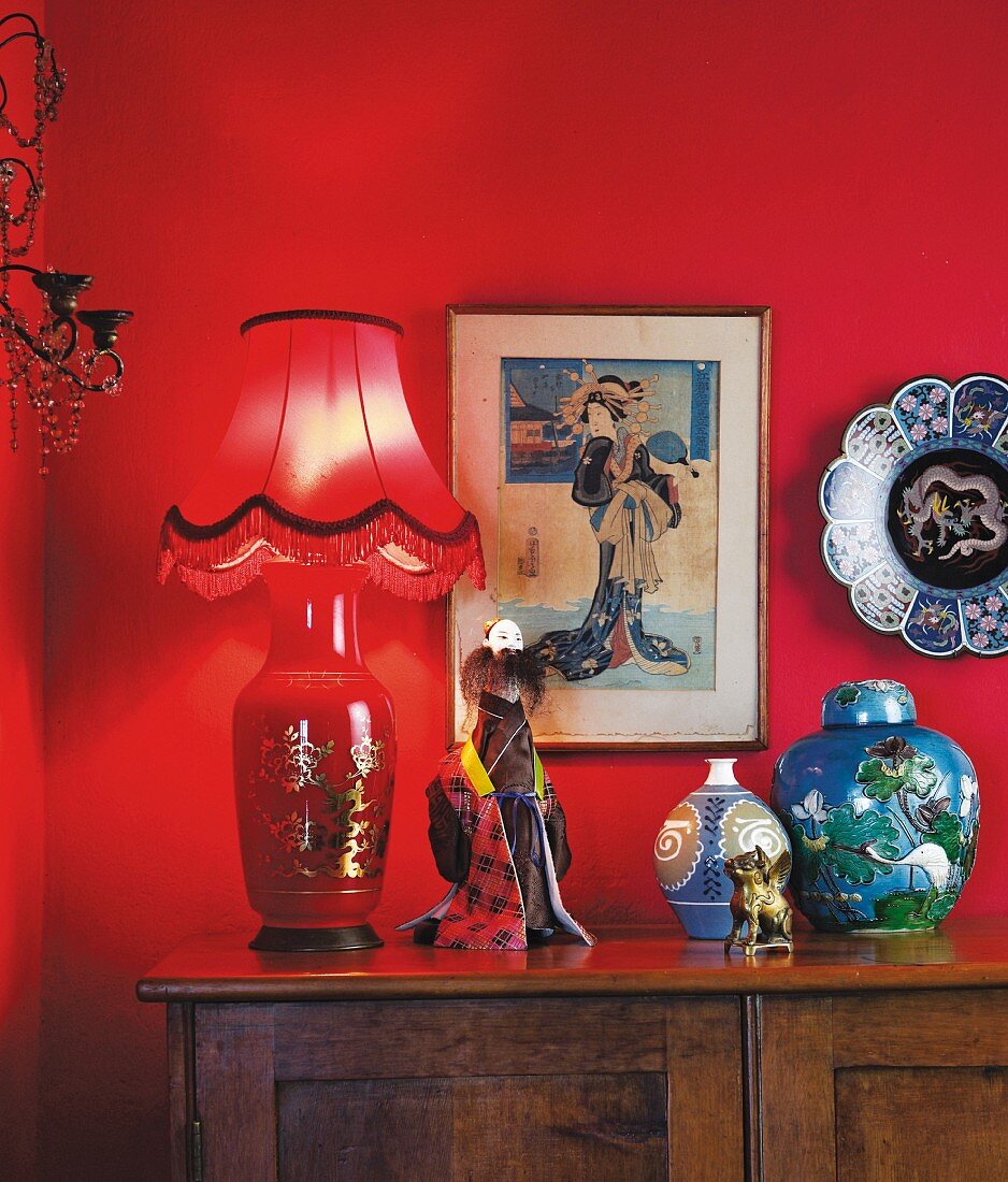 Japanese ornaments on and around cabinet against red-painted wall